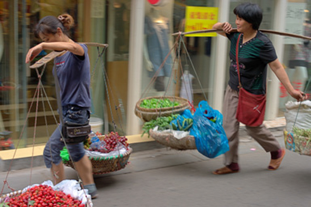 Chinese women in Nanjing carrying vegetables and fruits across town.