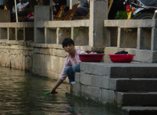 A woman washing clothes in a canal, Zhouzhang Jiangsu.